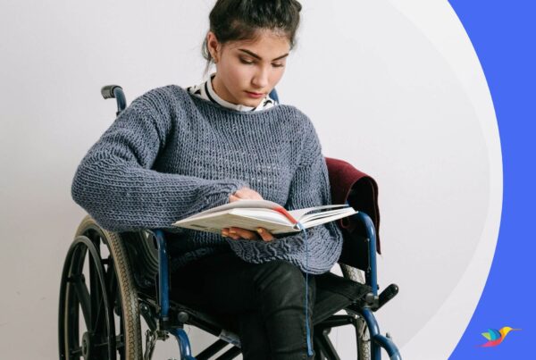 Foto de uma jovem sentada em uma cadeira de rodas segurando um livro e lendo.