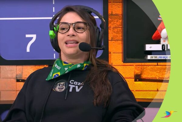 Foto de Lais Souza falando e usando uma armação e óculos preta e um Colibri verde preso a ele. Ela também usa um headset com um microfone.